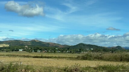 Wide agricultural areas unfold gradually as the camera advances, motion smoothing fields and plantations into a continuous countryside panorama. Open countryside.