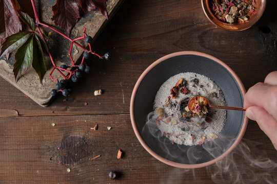 Mabon incense ritual - placing dried herbs and resins on a burning on charcoal