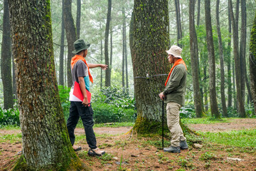 Two Hikers Strategizing With Map and Compass in Misty Pine Forest Planning Their Next Adventure