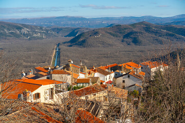 Wide panoramic view of red tiled rooftops and rolling hills surrounding Motovun, Croatia, under clear daylight at winter 
