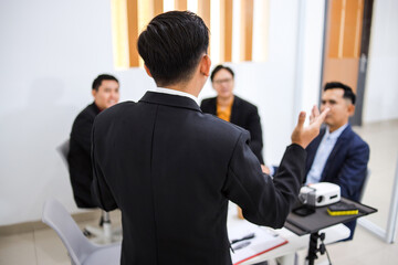 Confident Businessman Presenting Ideas To Colleagues In Modern Office Setting