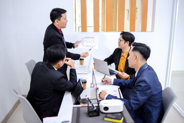 Business Team Engaged In Productive Meeting With Laptops And Documents In Modern Office Setting