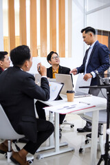Professionals In Modern Office Setting Engaged In Collaborative Meeting With Laptops And Documents