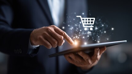 Close-up of a man in a dark suit using a tablet with a glowing shopping cart icon and network connections above it, suggesting online shopping and e-commerce, dark background.
