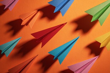 Diagonal display of colorful paper planes with a warm orange background