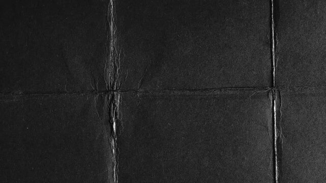 Black paper folded into grid with visible creases texture