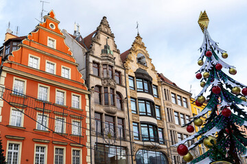 Fototapeta premium Colorful historical buildings in Wroclaw showcase unique architectural styles during the Christmas season, with a decorated tree adding festive spirit. Perfect for travel and seasonal promotion.