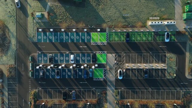 Top down aerial view of EV electrical vehicle charging hubs, modern car technology, no fossil fuels at a service station in the United Kingdom.
