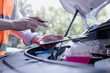 Technician using tablet to analyze electric vehicle system with virtual interface, inspecting battery and engine diagnostics inside car. Concept of EV maintenance and smart technology.