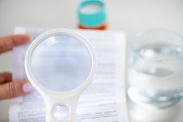 Using a handheld loupe to read small medication instructions. Highlights accuracy, careful review, and responsible medication management.