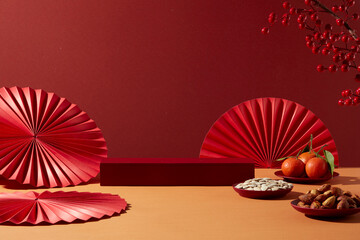 Chinese New Year background with red podium, decorative fans and traditional snacks, seeds. Clean layout with red tone for product display and branding