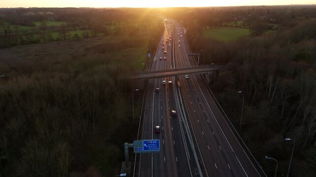 Aerial drone view of motorway highway at sunset, motion blur for traffic travelling, golden light near Birmingham, United Kingdom.