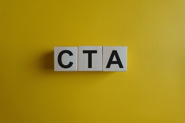 Call to action lettering on wooden blocks against a vibrant yellow background viewed from directly above