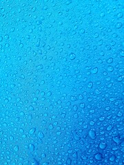 Water droplets on fabric. A blue background shows raindrops on a blue fiber waterproof fabric. The...