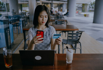 Credit card, mobile phone and woman on laptop in cafe online shopping, ecommerce website payment for sale. Asian woman, retail customer and smartphone bank app or internet finance in coffee shop.