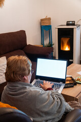 Senior woman at home enjoying using the laptop sitting on a armchair