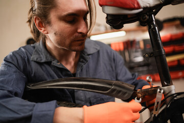 Bike service, repair and upgrade concept. Male Cycling mechanic fixing bicycle wheel working in...