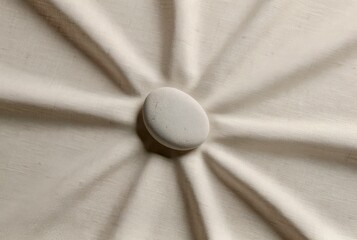 Sunlight casts shadows on fabric with a central stone accent during a quiet afternoon