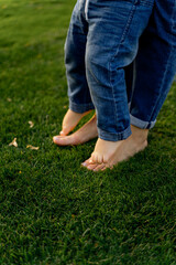Child Standing on Parent Feet on Green Grass