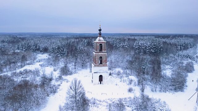 Drone ascends above historic bell tower revealing vast snowy forest horizon, delivering cinematic winter scenery for travel marketing, storytelling, and branding projects