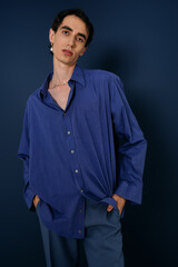 Obraz premium Stylish man poses confidently in blue ensemble against a solid backdrop