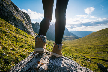 Successful woman backpacker hiking on sunset alpine mountain top