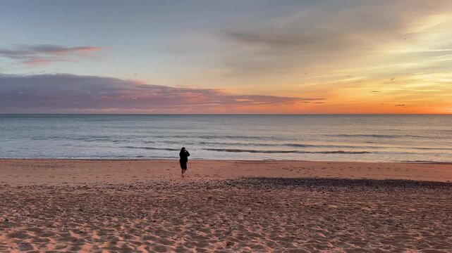Silhouette Woman Looking At Serene Waves Reaching Shore During Sunset