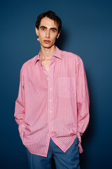 Handsome stylish man poses confidently against a vibrant blue backdrop in trendy attire