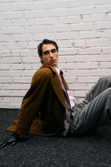 Naklejka premium Stylish man poses confidently in modern fashion setup with textured backdrop