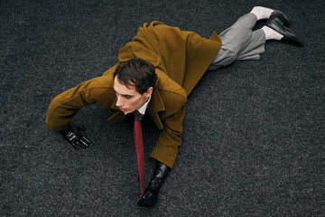 Stylish man in a dramatic pose on textured black carpet during an artistic photo shoot