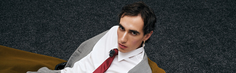 Stylish man lounging casually in modern attire on a textured background