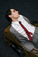 Stylish man poses elegantly on the floor in a modern, artistic fashion setting