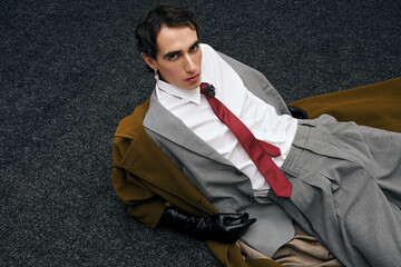 Handsome stylish man in elegant outfit posing on textured floor in contemporary setting