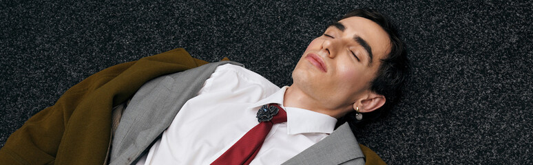 Stylish man rests confidently on floor in modern fashion statement under soft lighting