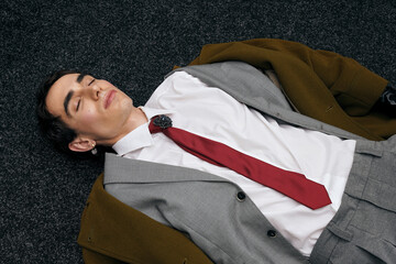 Stylish man in a tailored suit rests on a dark carpeted floor in an artistic setting