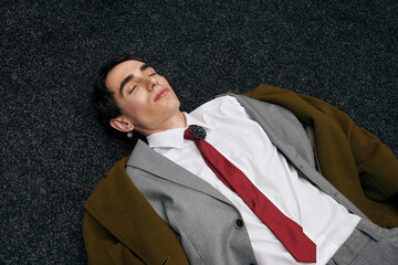Stylish man relaxing on a textured floor, showcasing modern fashion and elegance