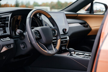 A premium, modern brown car interior, leather steering wheel, large navigation screen, air ducts, deflectors on the car panel. Interior details.