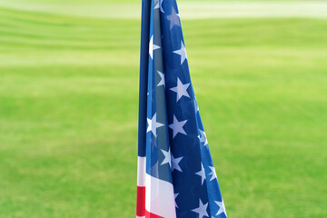 USA. Flag on golf course represents American spirit and memory of the game with green grass in background