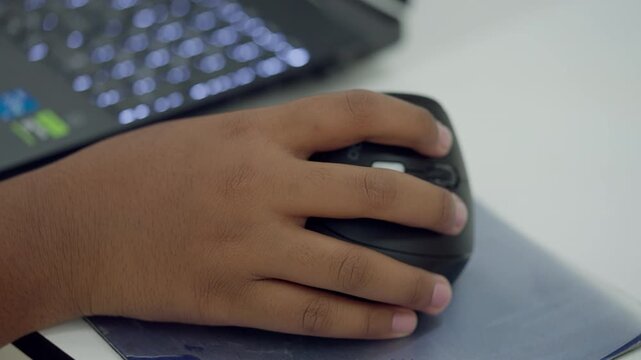 Close-up of a student s hand holding a computer mouse during a STEM programming or robotics class, working on coding or electronics project.