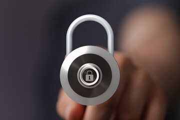 A close up shot of a silver padlock held by a person signifying security, safety, and protection....