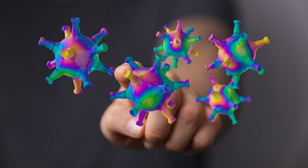 Abstract rendering of viruses in vibrant, rainbow colors held in a human hand, representing health,...