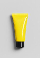 Yellow cosmetic tube with black cap isolated on light gray background