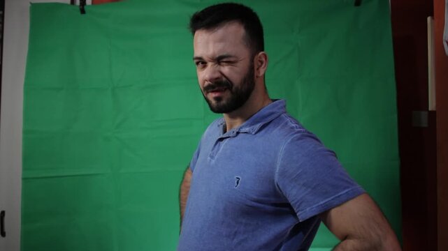 Portrait of a man making hand gestures in front of a green background.