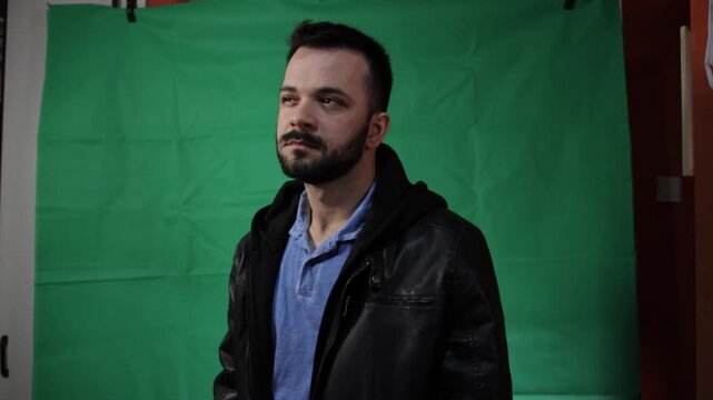 Actor looking upwards curiously on a green screen studio background.