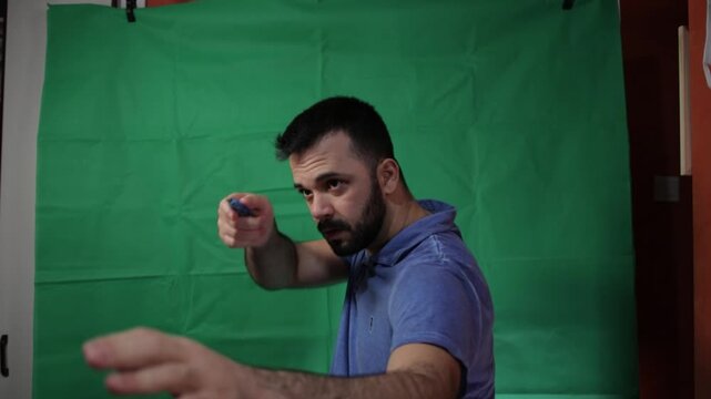 Young man in a blue shirt pointing to the side on a chroma key background.