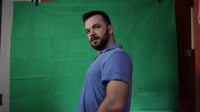 Man in casual blue shirt looking at the camera on green screen.