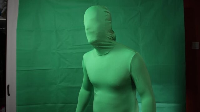 Actor wearing a green morph suit for visual effects on green screen.