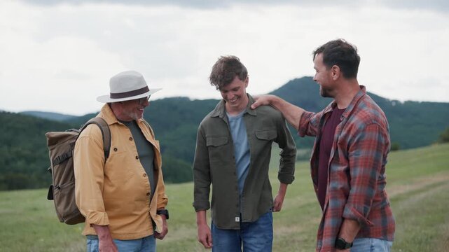 Grandfather, father and teen boy hiking togeter in nature, spending time together during weekend.