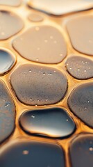 Smooth water drops form a liquid pattern on a textured surface with tiny bubbles.