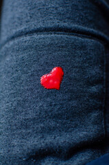 A small red heart painted on gray pants